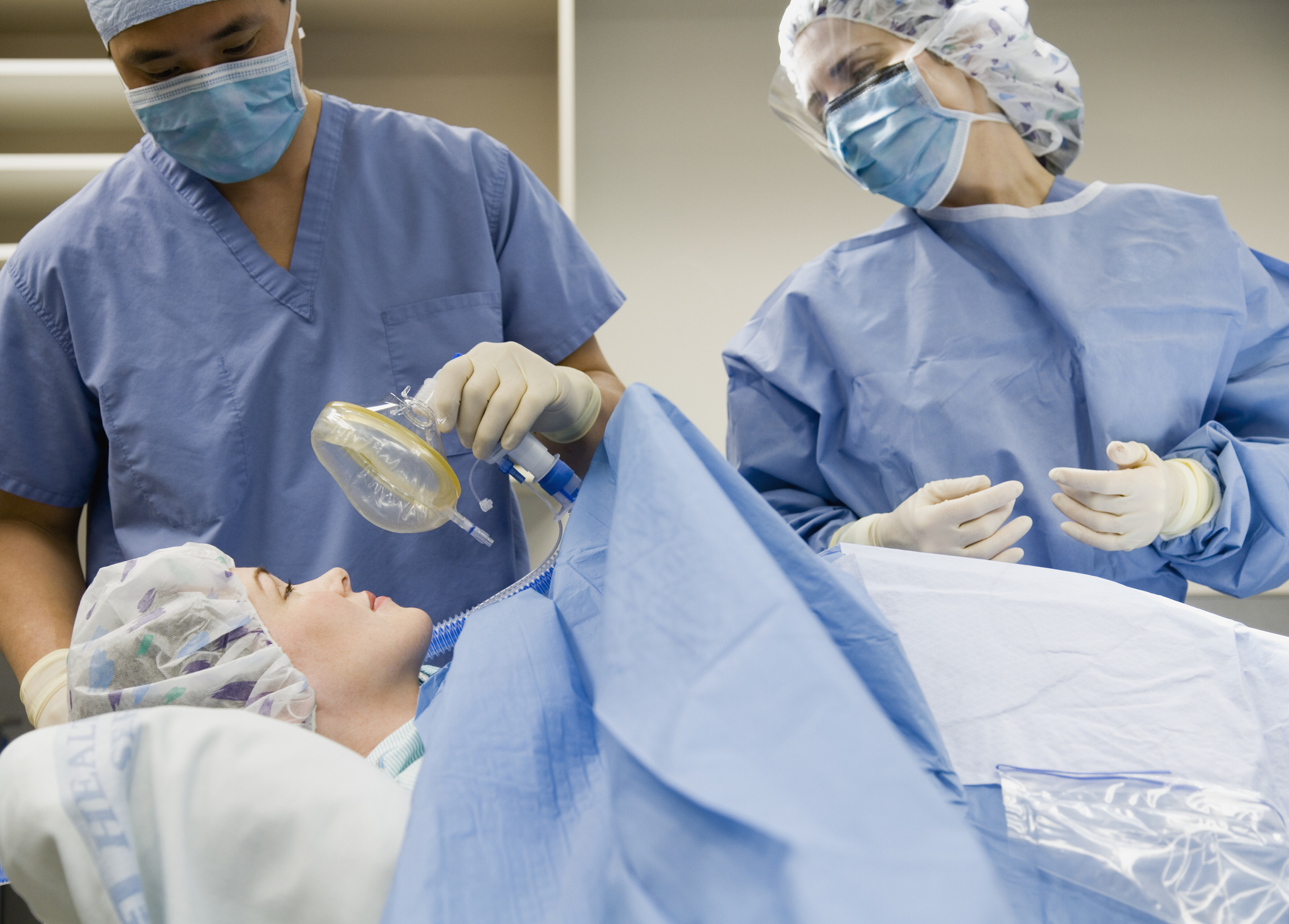 Nurse supplying patient with anesthesia beside surgeon